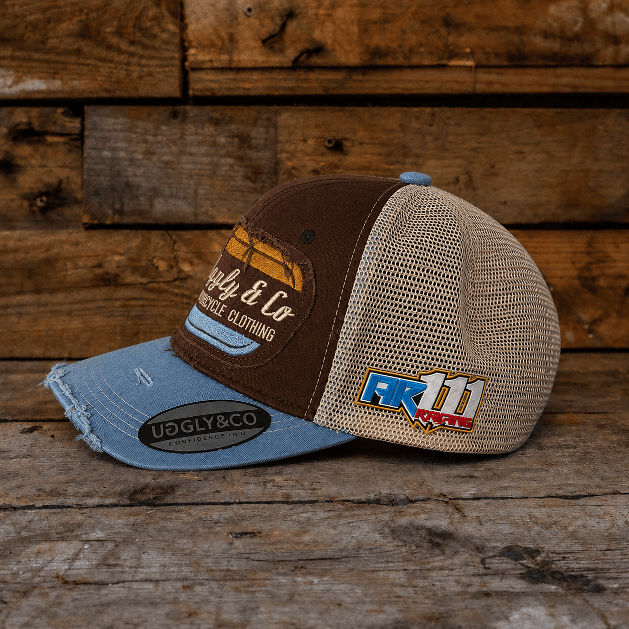 Dusty blue and brown flat track trucker cap by Uggly and Co, featuring a diamond logo on the side.