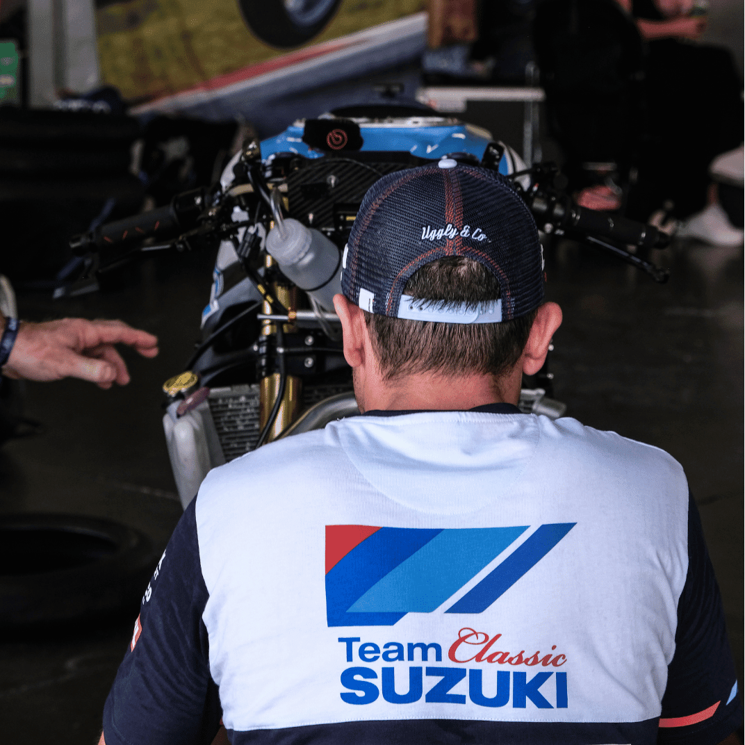 Uggly and Co Team Classic Suzuki Trucker Hat featuring a racing-style design with adjustable mesh back and iconic Suzuki logo.