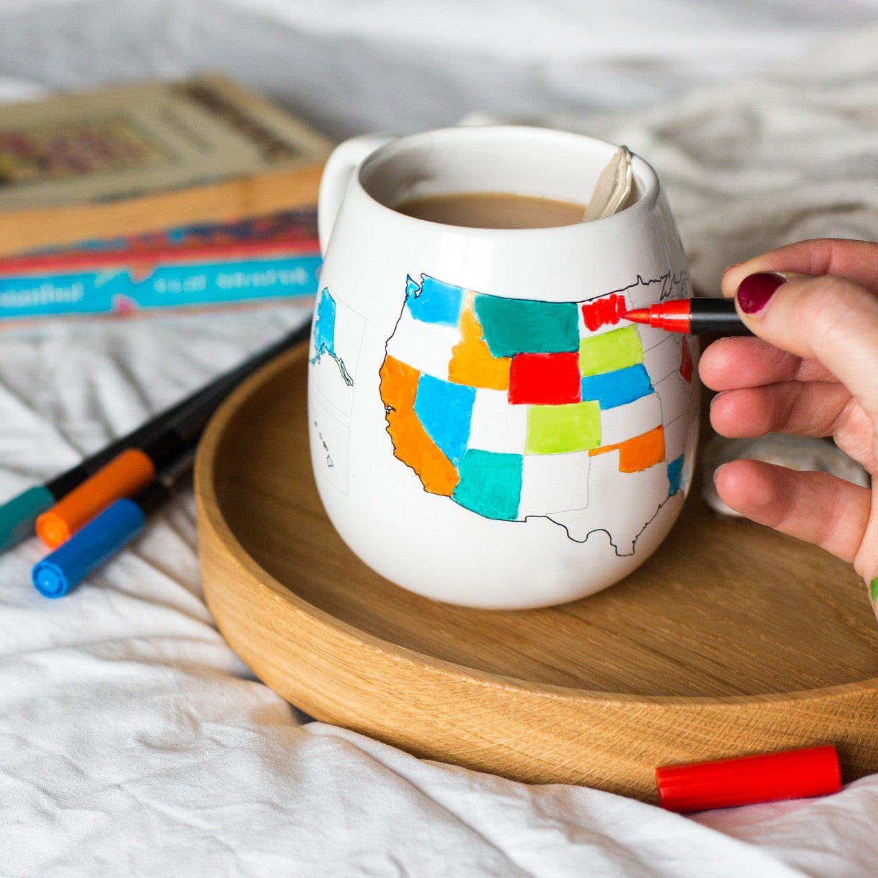 Set of four Trouvaille ceramic pens with colorful ink, placed near a coffee mug and tray for coloring and artistic projects.