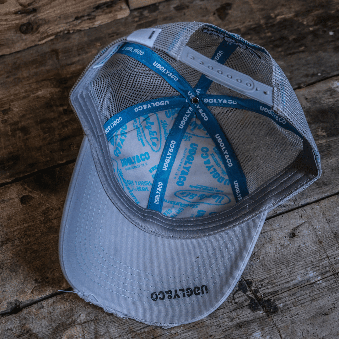 Steel grey Uggly and Co Trucker Cap featuring Davey Todd merchandise logo, casual cap with adjustable strap and mesh back.