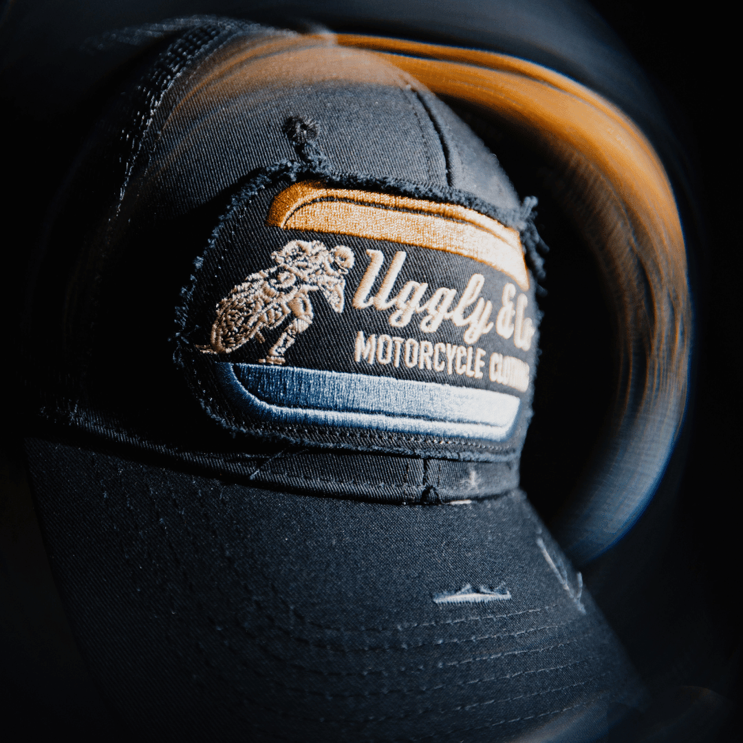 Black flat track trucker cap by Uggly and Co featuring a classic mesh back and adjustable snap closure.