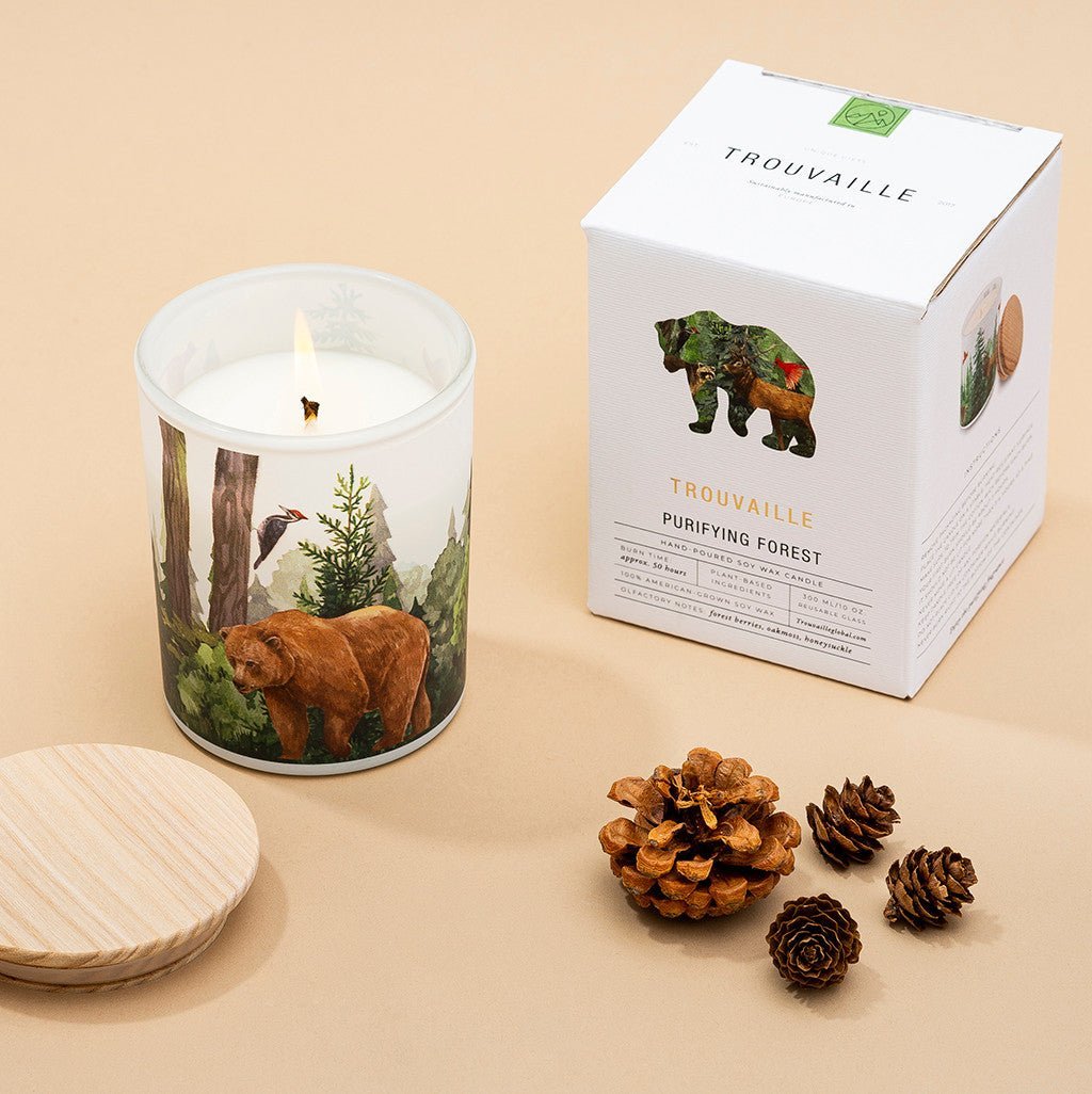 Trouvaille Forest Soy Scented Candle with eco-friendly packaging, featuring balsam fir and wild berries, set against a forest background.
