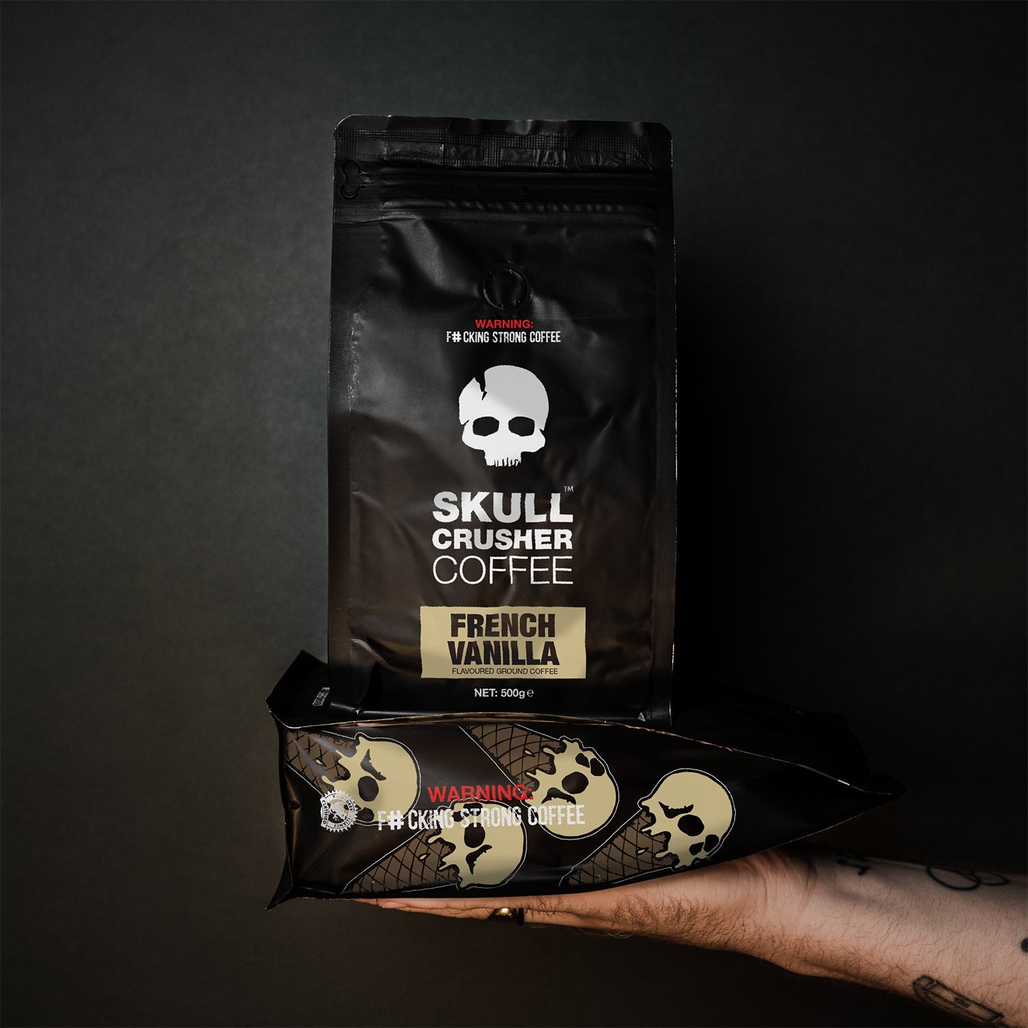 Skull Crusher Coffee French Vanilla flavored coffee bag with vanilla beans and coffee beans on a rustic surface.