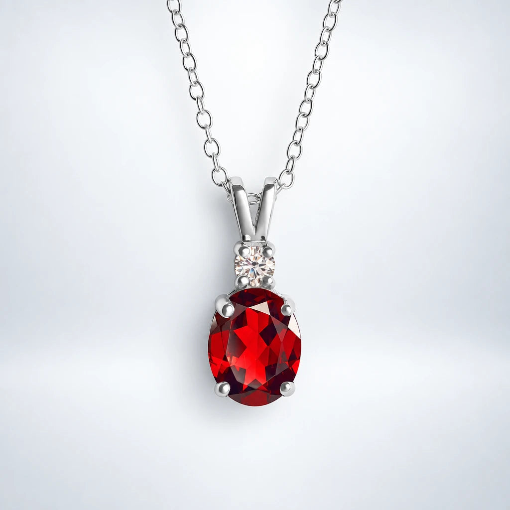 Sterling silver garnet pendant necklace by Vianne Jewellery displayed on a silver studio background.