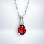 Sterling silver garnet pendant necklace by Vianne Jewellery displayed on a silver studio background.
