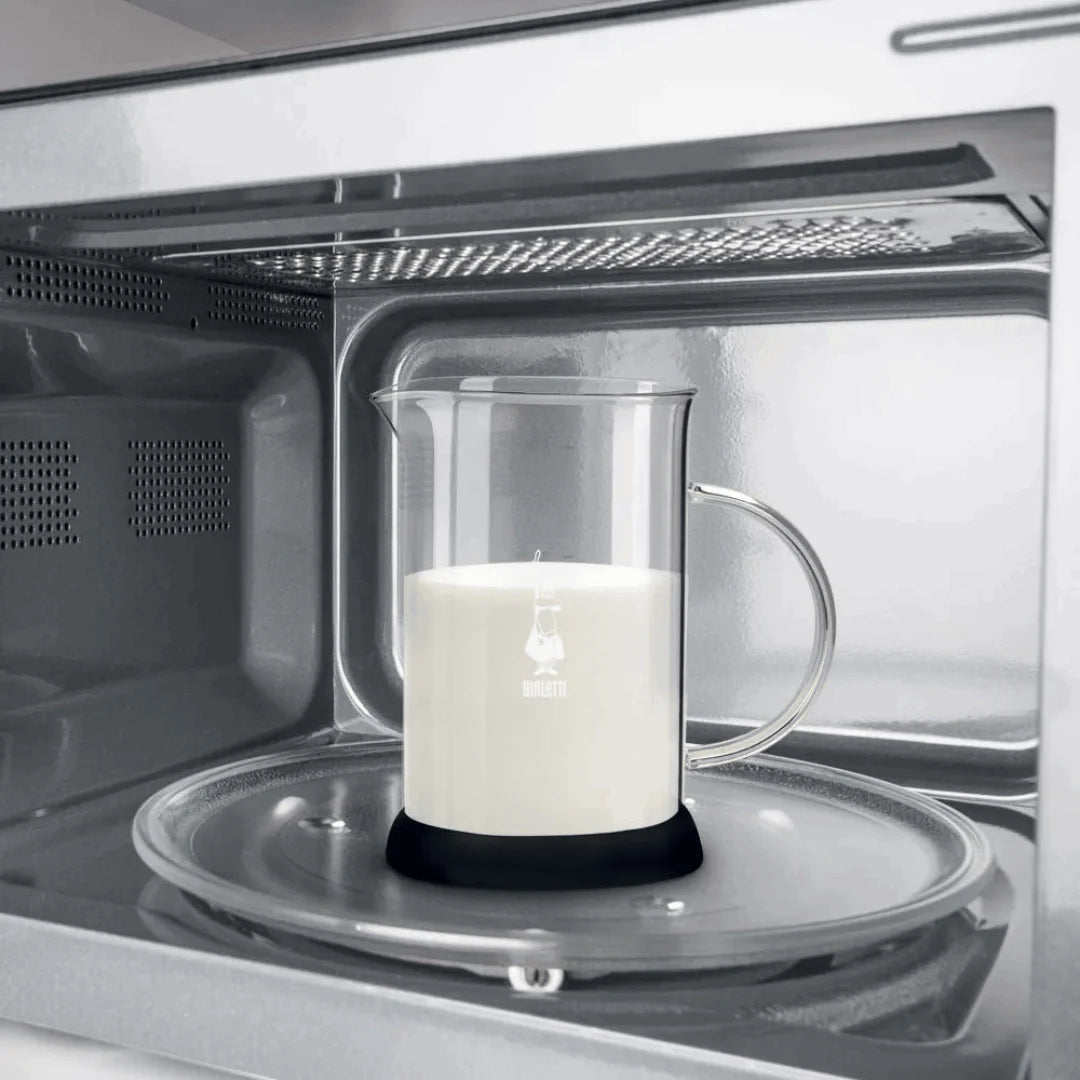 Bialetti Tuttocrema glass milk frother by Brew Italia with clear glass body and handle, used for frothing milk.