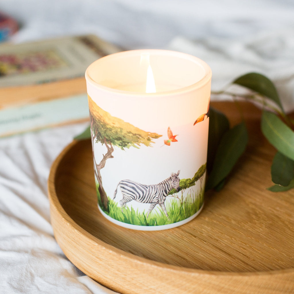 Trouvaille Grassland Soy Scented Candle with uplifting citrus fragrance, showing a lit candle in a glass jar on a wooden surface.