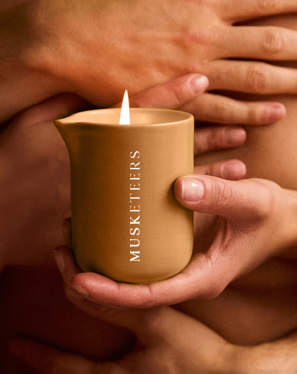 Musketeers Mandarin & Sandalwood scented massage candle burning with soft glow and melted wax for massage and relaxation.