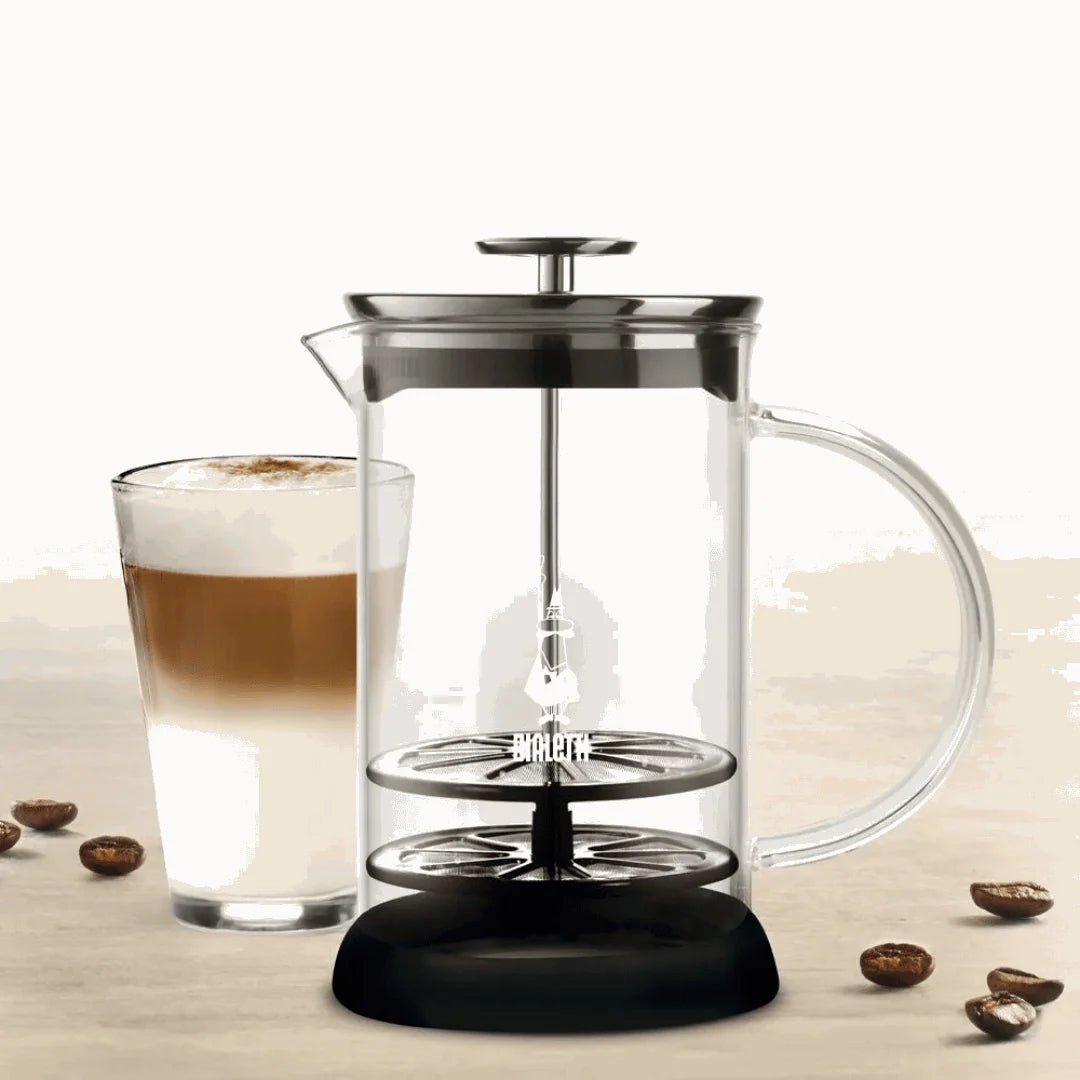 Bialetti Tuttocrema glass milk frother for hot latte, with stainless steel handle and clear glass body for frothing milk.