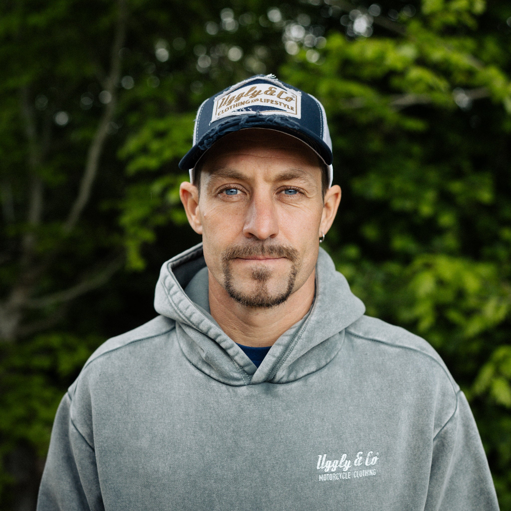 Night blue and gold diamond trucker cap by Uggly and Co, worn by motorbike rider Josh Brookes outdoors.