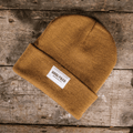 Mustard Uggly and Co beanie made of soft knit fabric, featuring a snug fit and a folded brim for warmth and style.