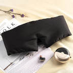 Black silk sleep mask by DREAMSILK, soft and luxurious sleep accessory with smooth fabric and adjustable strap for restful nights.