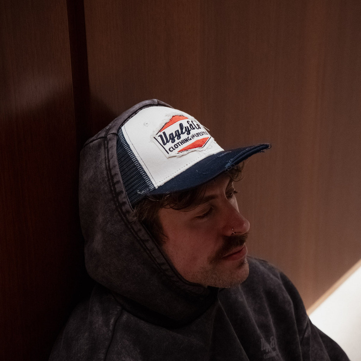Navy blue and white diamond pattern Uggly and Co trucker cap with mesh back and curved brim.
