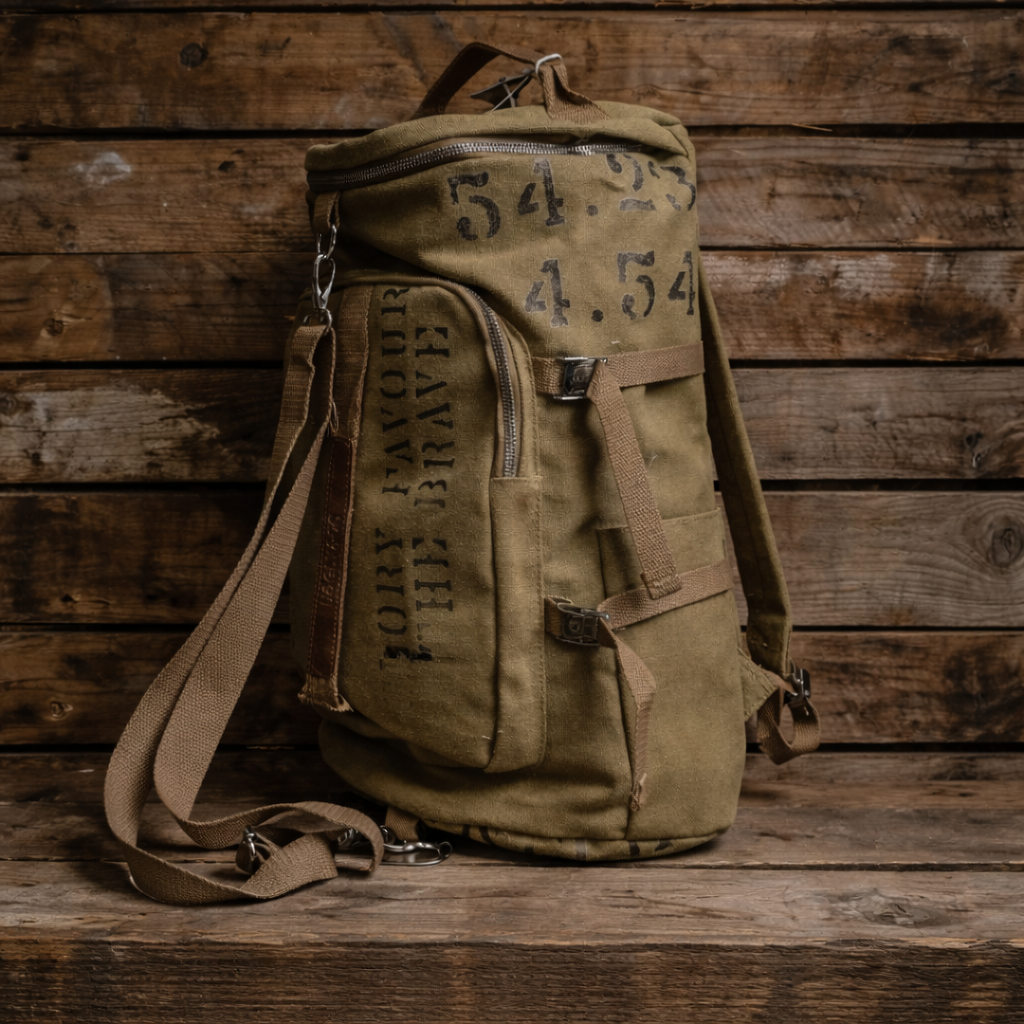 An olive green canvas backpack with military-style stenciled markings, displayed on a rustic wooden plank surface.