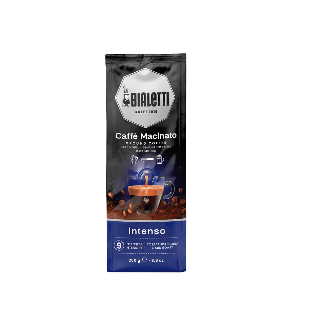 Bialetti Brew Italia Omni Ground Coffee Intenso in a bag with a dark roast label and coffee beans in the background.
