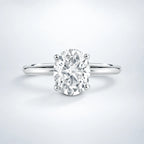 Oval moissanite engagement ring in sterling silver with a solitaire design, displayed on a neutral studio backdrop.