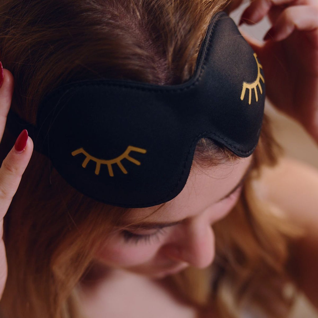 Close-up of SMUG contoured 3D blackout sleep mask in black with wink print, designed for comfortable sleep and complete light blocking.