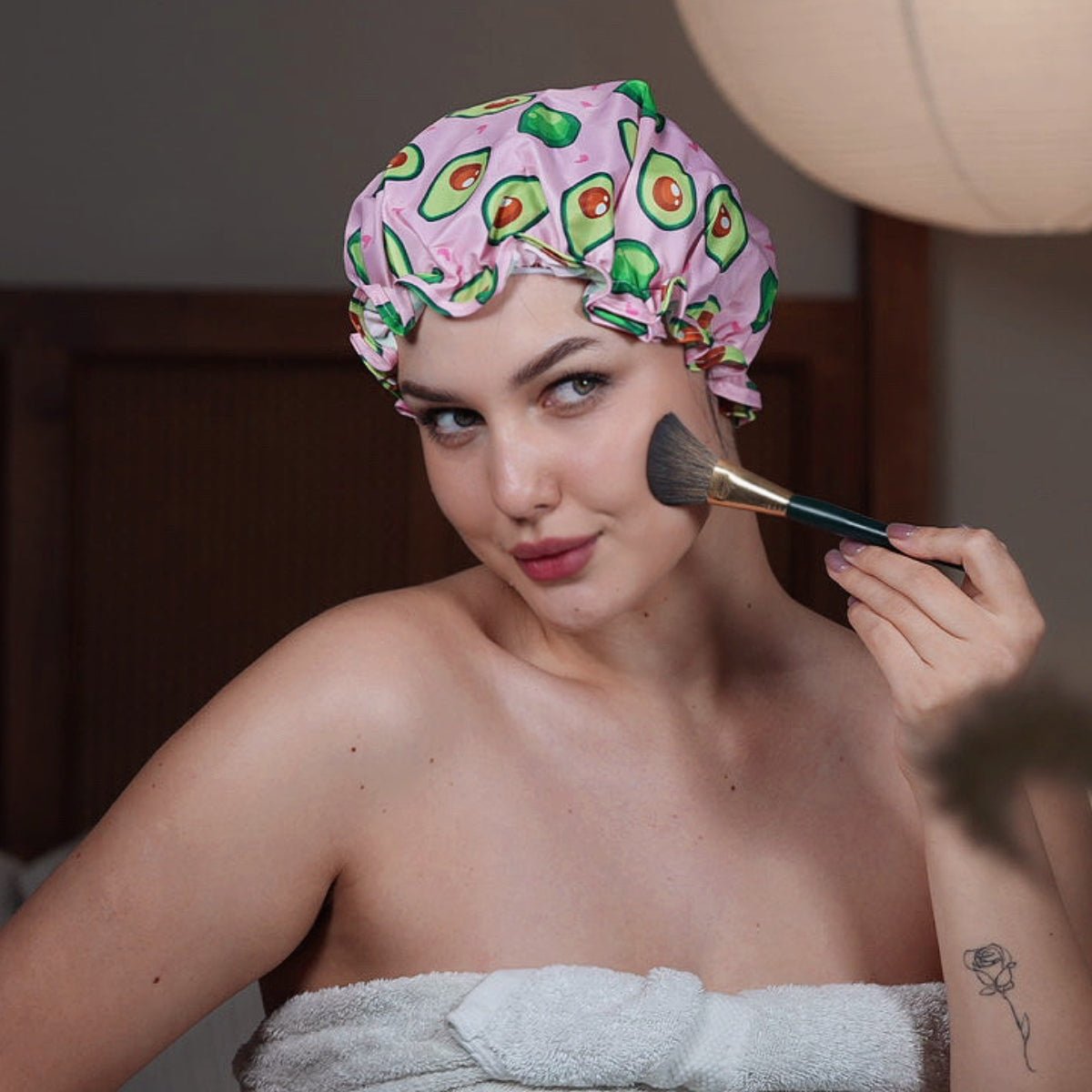 SMUG avocado print shower cap with waterproof material, shown next to a towel and makeup brushes.