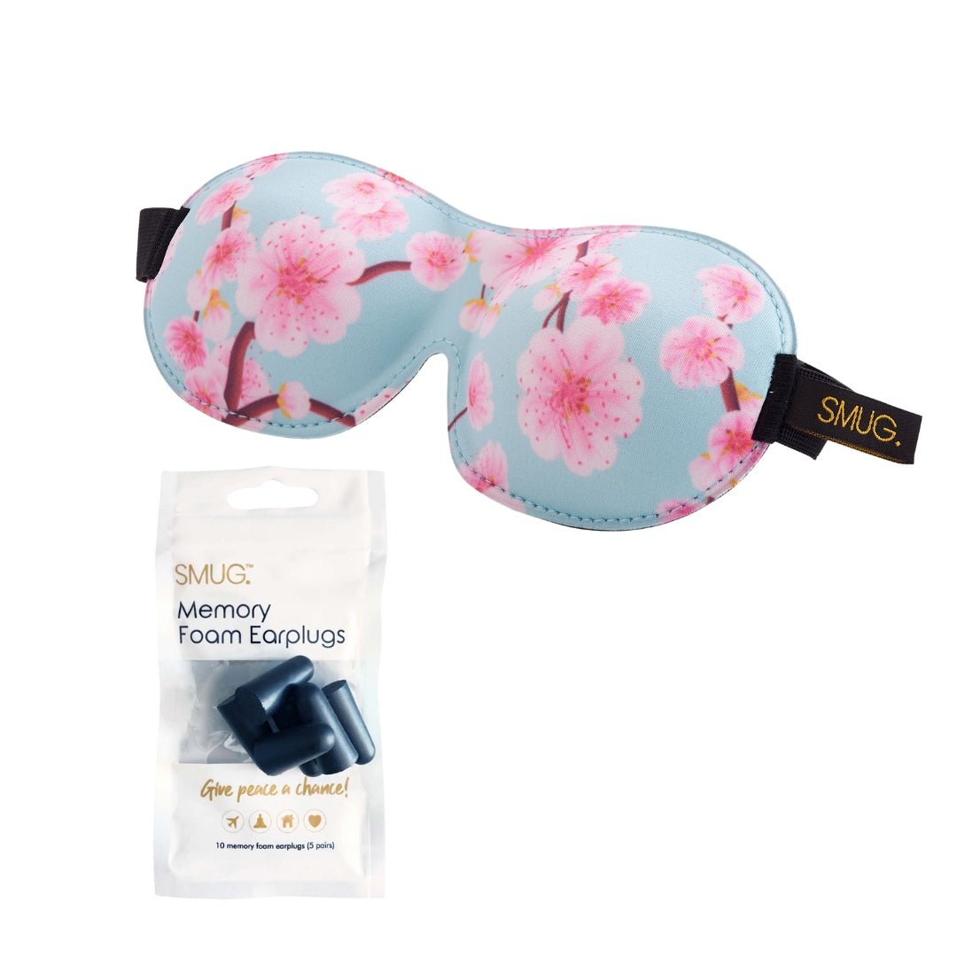 Contoured black sleep mask with cherry blossom print by SMUG, featuring 3D design and earplug for comfortable blackout sleep.