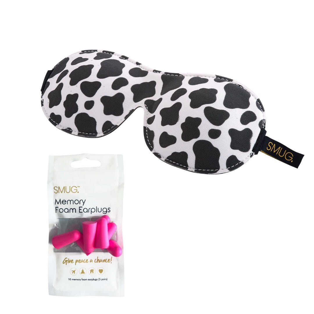 Contoured SMUG blackout sleep mask with cow print and earplugs for comfortable, light-blocking sleep.