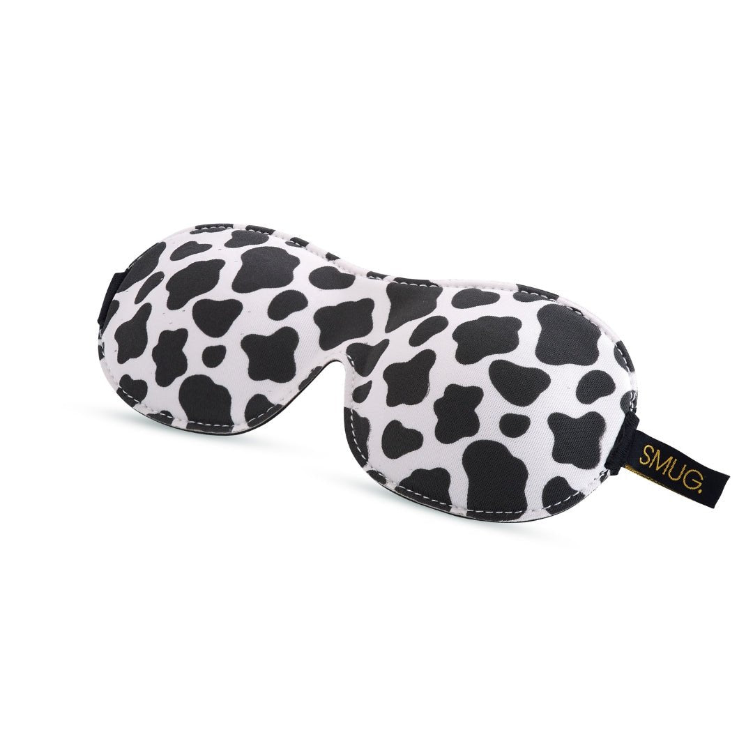 Contoured 3D black blackout sleep mask with cow print design by SMUG, featuring a comfortable fit for restful sleep.