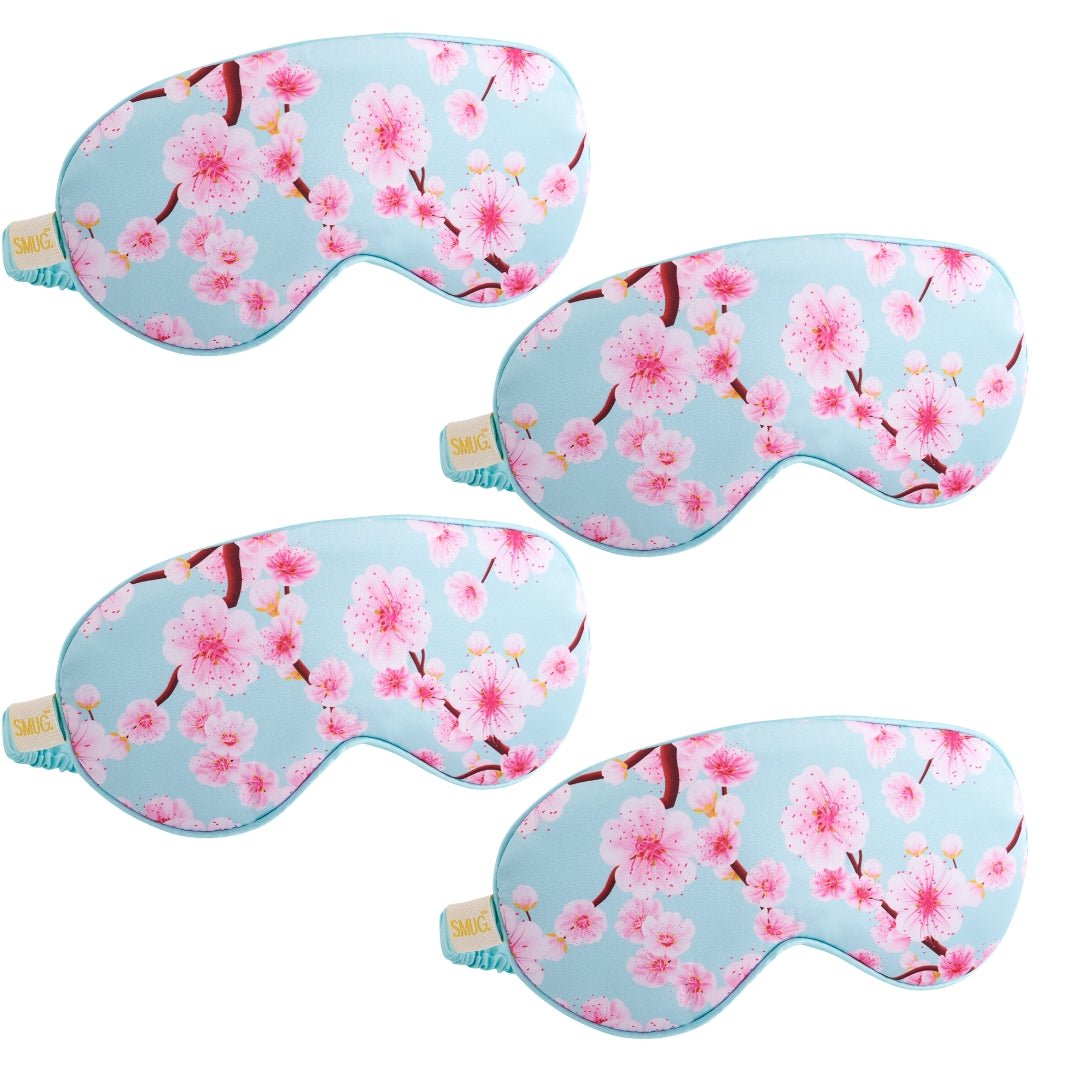 Set of satin sleep masks by SMUG in various designs, including a cherry blossom pattern, designed for comfortable sleep.