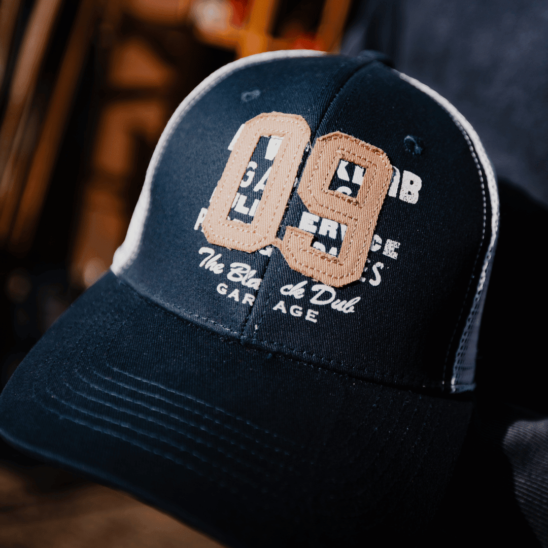 Black Uggly and Co trucker cap with navy "09" parts and spares logo, featuring mesh back and adjustable snap closure.
