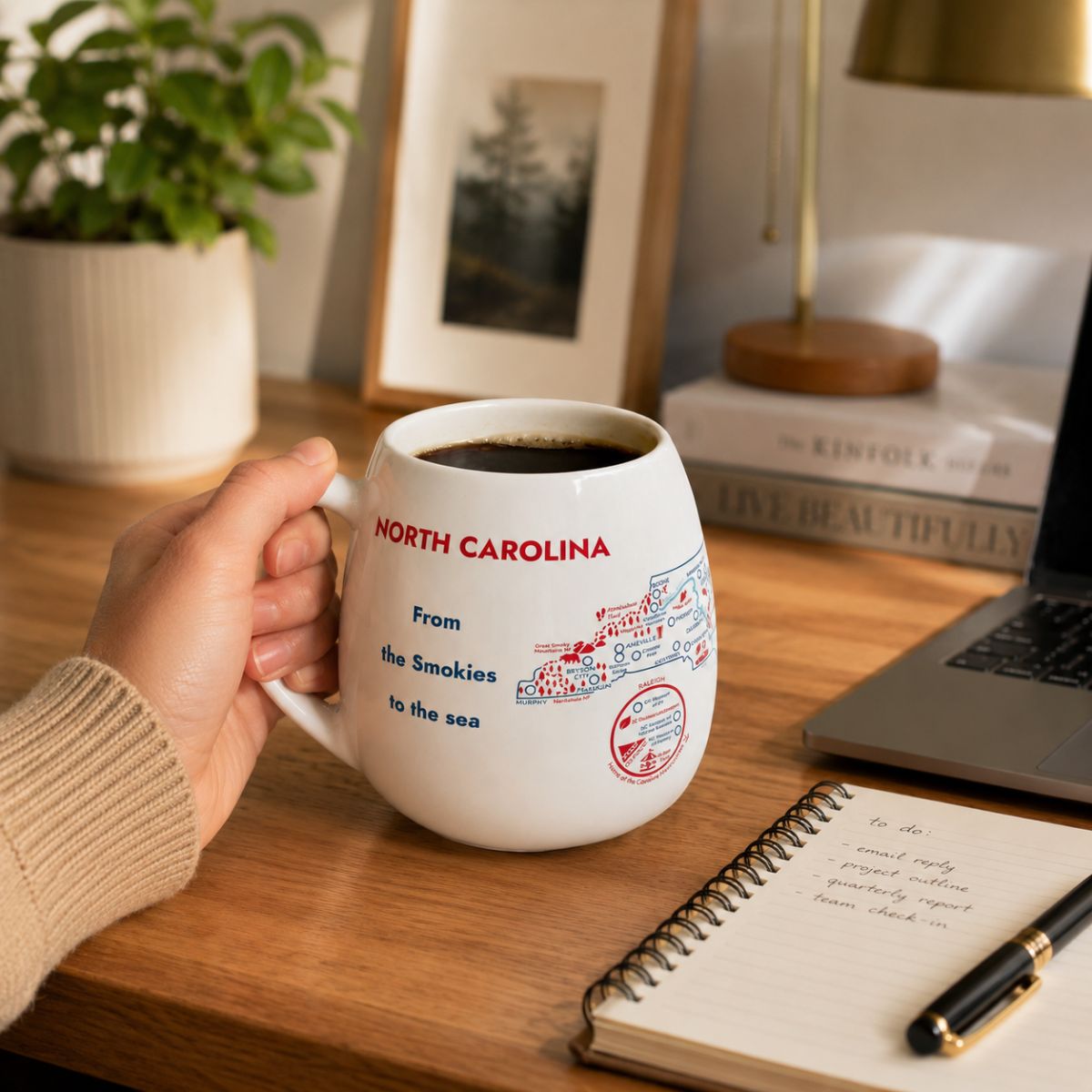 Trouvaille North Carolina map color-in travel mug with a white ceramic surface and a black lid featuring a detailed state outline.