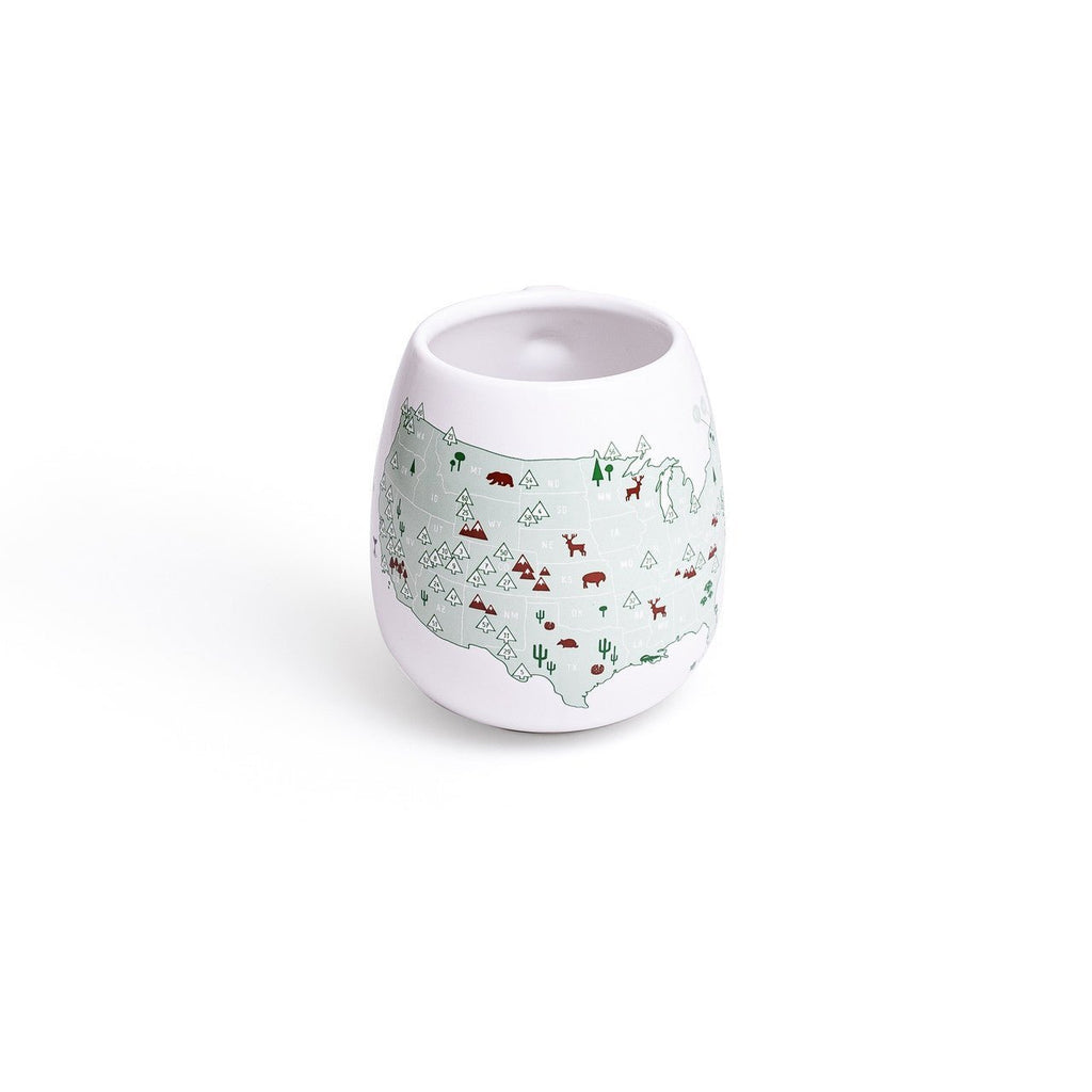 Color-in mug featuring US National Parks design by Trouvaille, with a blank space for coloring and detailed park illustrations.