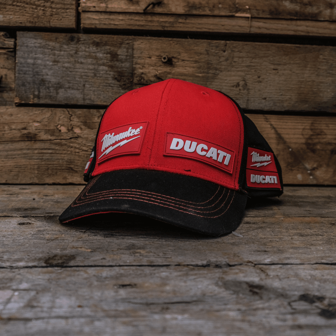 Milwaukee Tools and Ducati team-wear trucker baseball cap featuring logos, worn by a rider, in a vibrant outdoor setting.