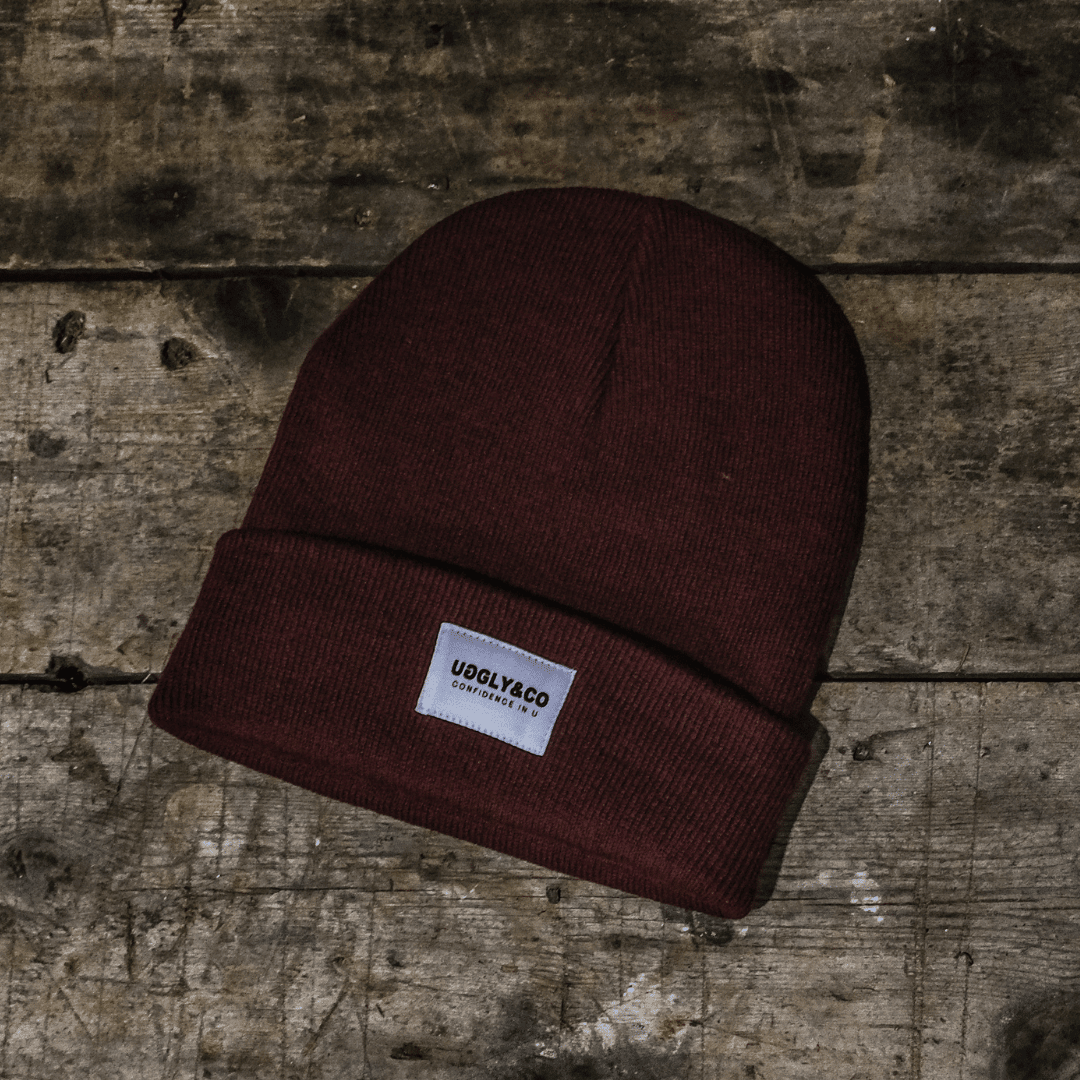 Burgundy Uggly and Co beanie hat made of soft knit material, styled for a cozy, casual look.