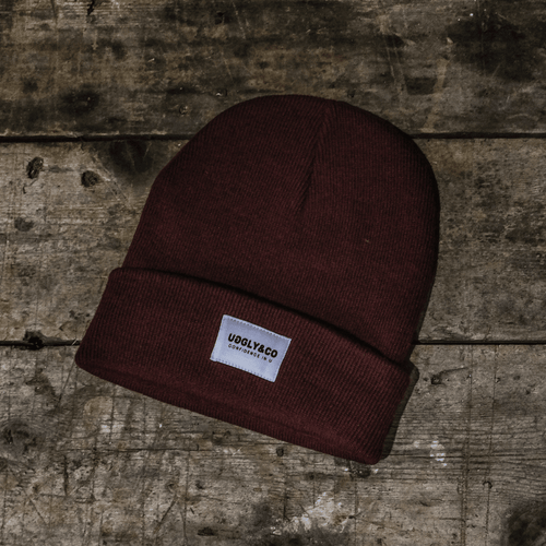 Burgundy Uggly and Co beanie hat made of soft knit material, styled for a cozy, casual look.