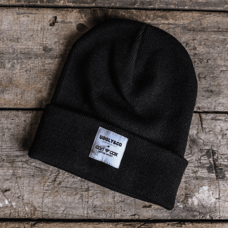 Uggly and Co Carl Cox Icon Beanie showing a black knit beanie with a bold logo design for motorsport enthusiasts.