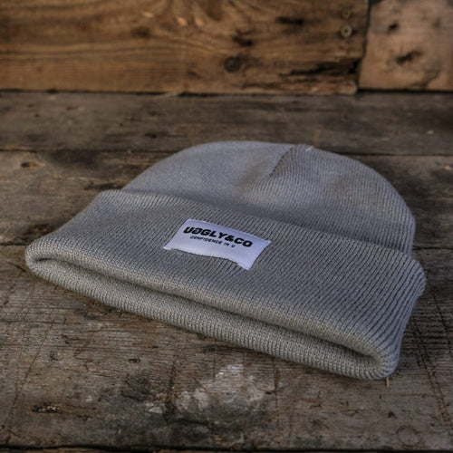 Grey Uggly and Co beanie, soft knit hat with folded brim, stylish and warm winter accessory, shown on a neutral background.