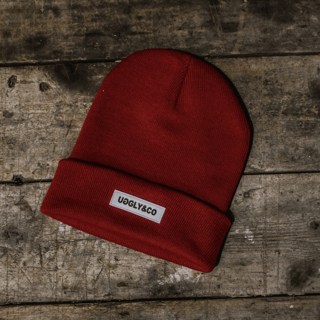 Red Uggly and Co beanie hat with a cozy knit design, perfect for warmth and casual style.