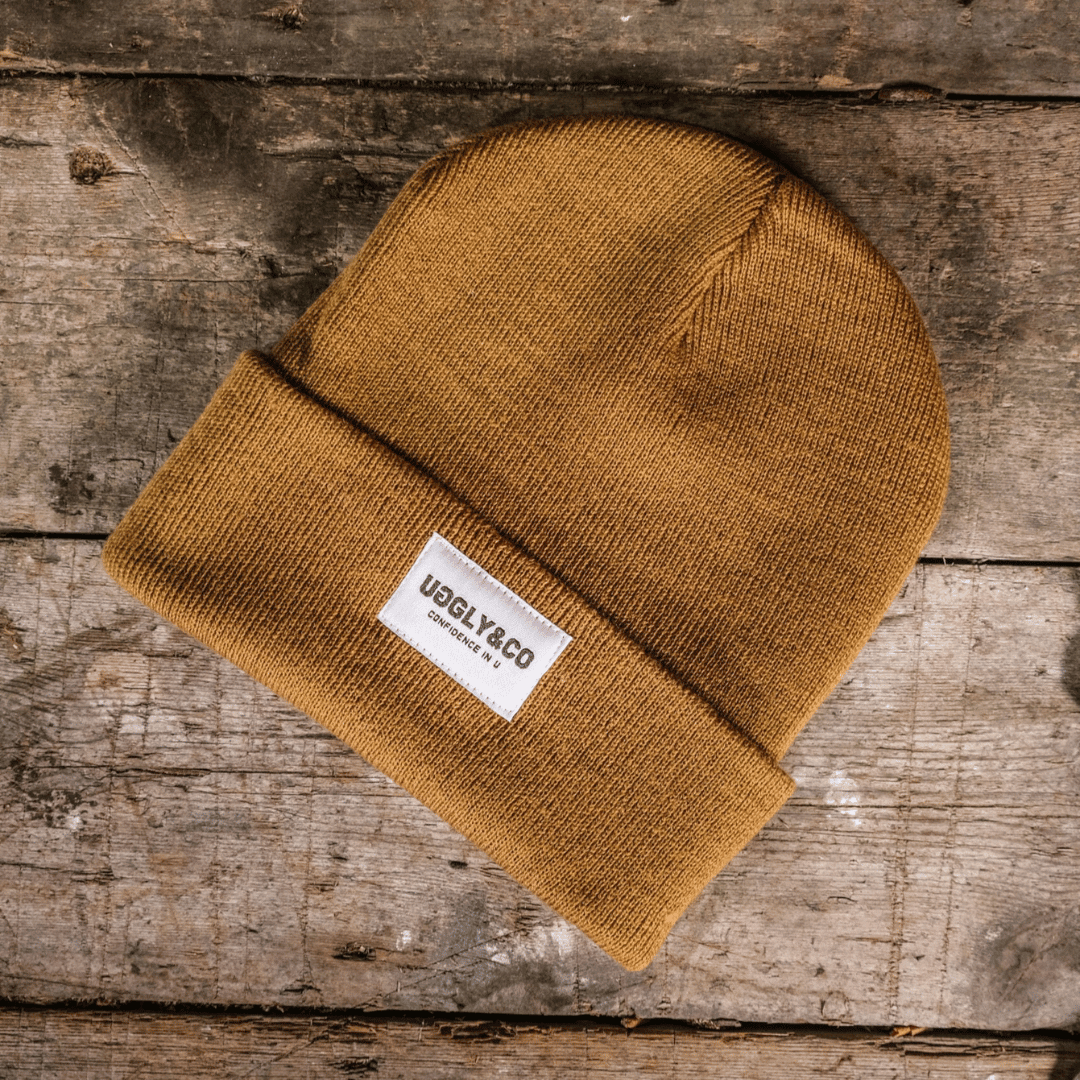 Mustard Uggly and Co beanie made of soft knit fabric, featuring a snug fit and a folded brim for warmth and style.