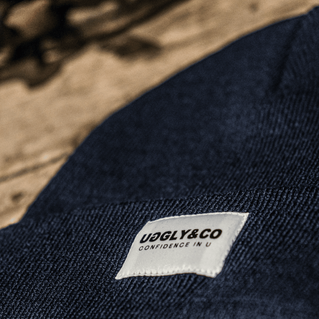 Navy Uggly and Co beanie hat with a snug fit, made from soft knitted fabric, perfect for cold weather.