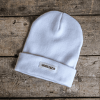 White Uggly and Co beanie hat shown, soft knit fabric with folded brim, stylish winter accessory.