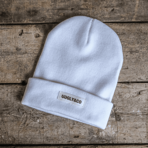 White Uggly and Co beanie hat shown, soft knit fabric with folded brim, stylish winter accessory.