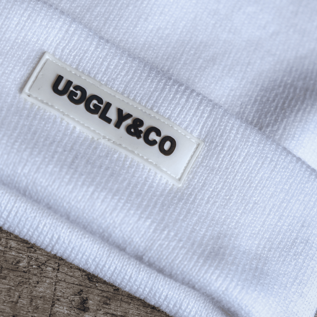 White Uggly and Co beanie displayed on a mannequin head, showcasing a cozy knit winter accessory.