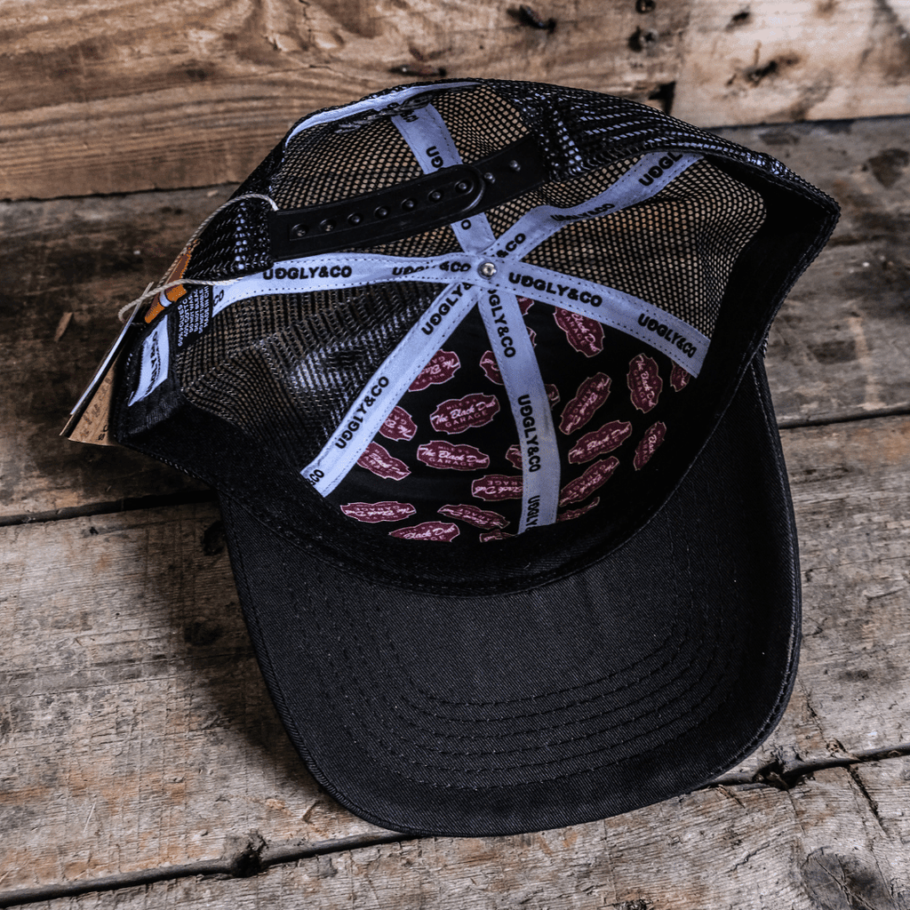 Black Dub Garage Trucker Cap by Uggly and Co featuring a classic trucker hat design with mesh back and adjustable snap closure.