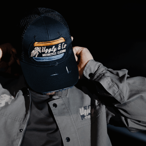 Black flat track trucker hat by Uggly and Co featuring a classic trucker cap design with mesh back and flat brim.