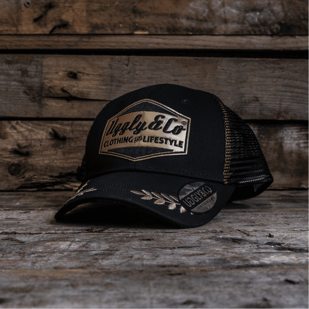 Black and gold Uggly and Co 'Podium' diamond trucker cap with heritage-style design, featuring a structured front and mesh back.