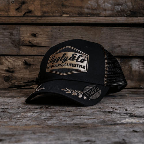 Black and gold Uggly and Co 'Podium' diamond trucker cap with heritage-style design, featuring a structured front and mesh back.