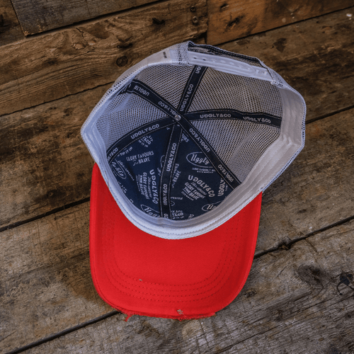 Blue and red diamond pattern trucker cap by Uggly and Co, featuring a classic mesh back and adjustable snap closure.