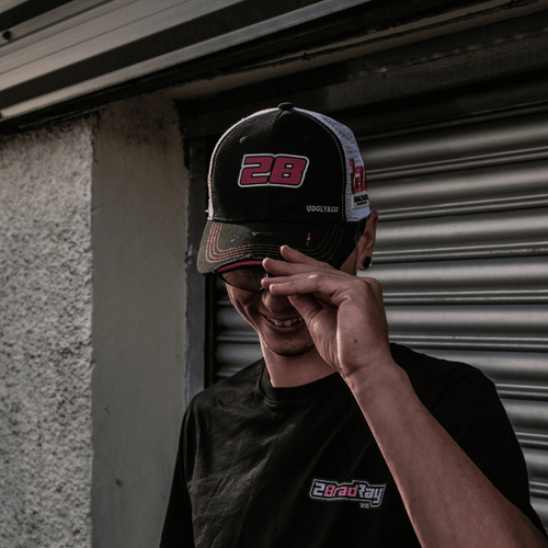 Uggly and Co Bradley Ray #28 trucker cap with logo, featuring mesh back and curved brim, on a model head.