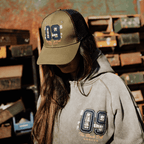Green Uggly and Co trucker cap with "09" design, adjustable mesh back and curved brim, casual headwear for everyday style.