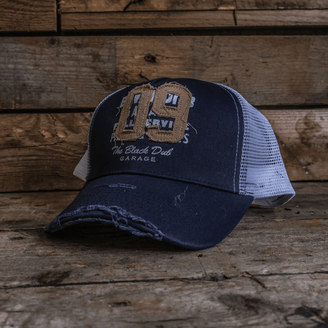 Navy Uggly and Co trucker cap with '09' logo, featuring mesh back and curved brim, in a retro biker style.