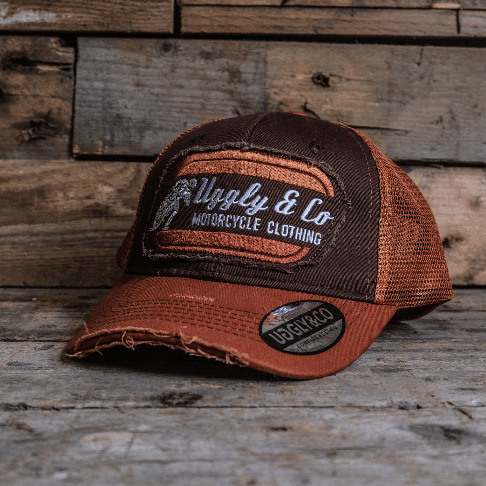 Vintage rust-colored flat track trucker cap by Uggly and Co featuring a classic mesh back and structured front panel.