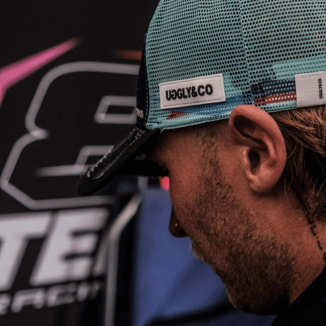 Black and blue Uggly and Co trucker cap featuring official Davey Todd merchandise logo, mesh back and curved brim.